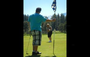 Brooke Laine putts while her son, Nik Olivares, holds the flag. Photo/Kathryn Reed