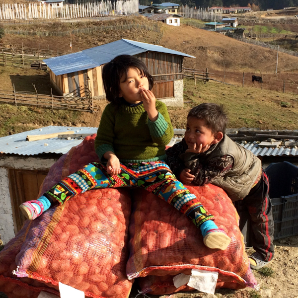 2.Bhutanese children from the eastern part of the country sitting on the local farm produce. Photo/Toni Neubauer