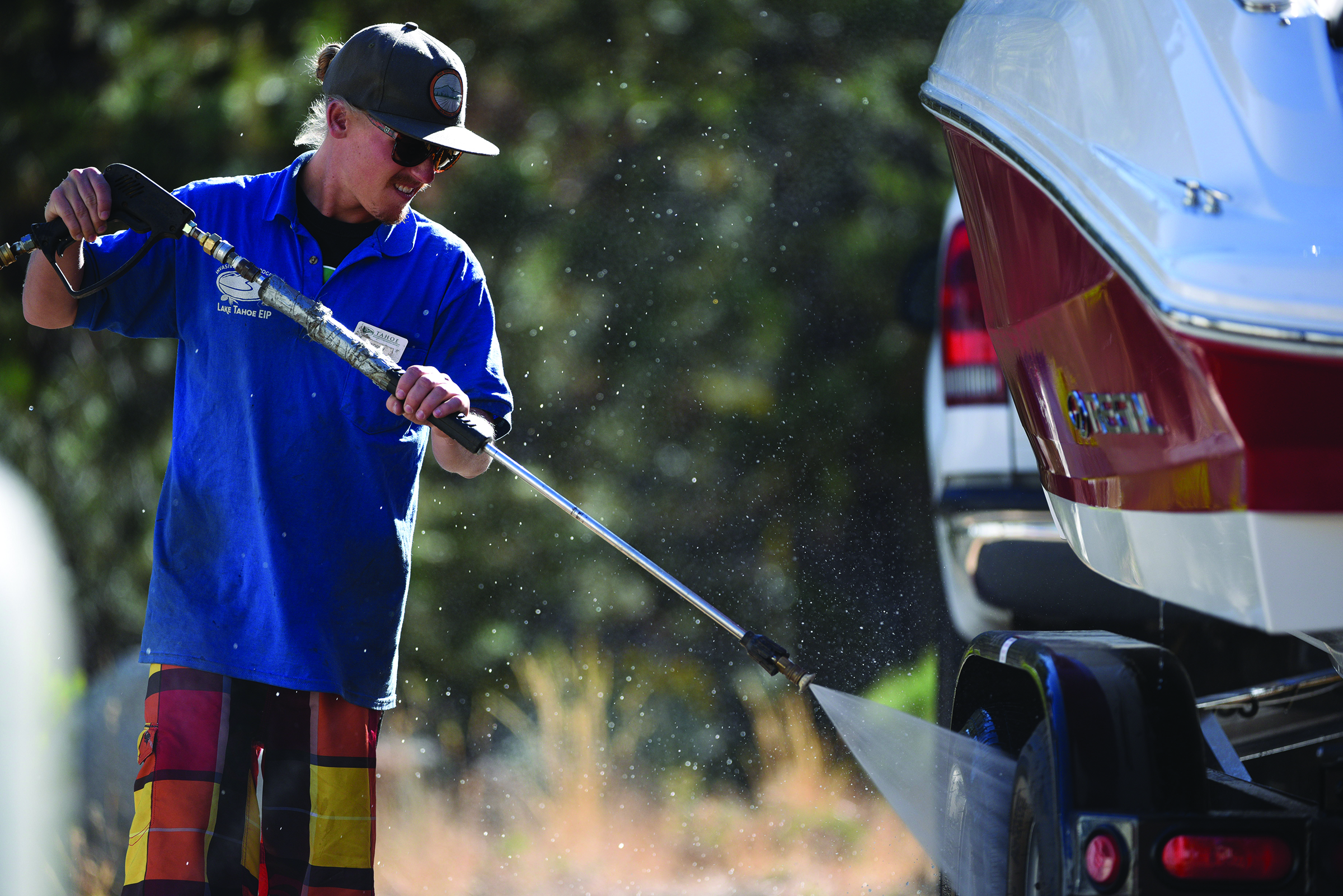 An inspector uses a pressure washer to decontaminate a boat before it is launched in Tahoe. Photo/Corey Rich